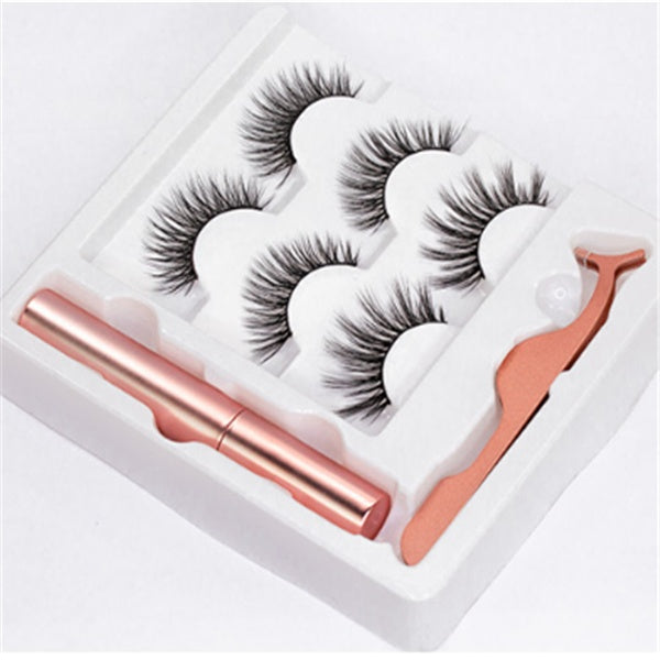 A set of magnetic eyelashes presented in a pink box with a pair of scissors and a tube of magnetic eyeliner, alongside two trays containing false eyelashes.