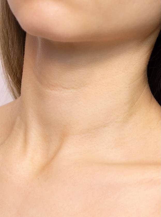 Close-up of a person's neck before used and shoulders with a neutral background
