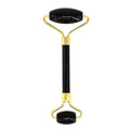 Black and gold facial roller on a white background
