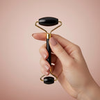 Black and gold facial roller on a white background