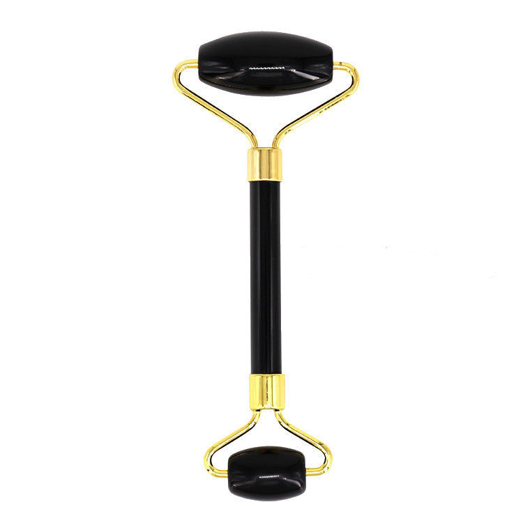 Black and gold facial roller on a white background