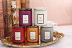 Five scented candles of different colors on a decorative tray with books in the background.