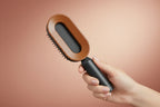 Hairbrush with brown bristle head and black handle on a white background