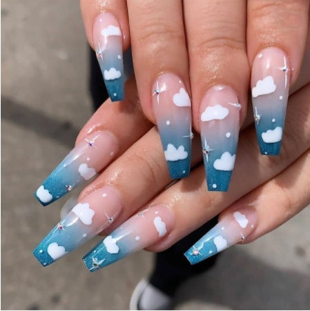 A hand with press-on nails featuring a blue and white cloud design.