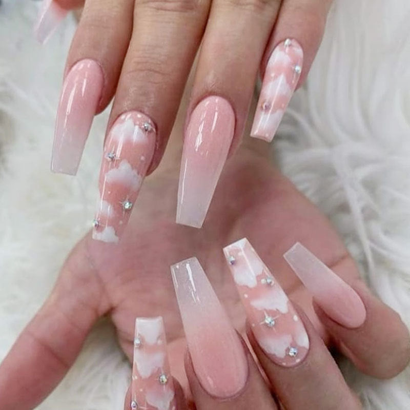 A set of false nails with a pink cloud design and rhinestone embellishments.