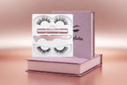 A set of magnetic eyelashes presented in a pink box with a pair of scissors and a tube of magnetic eyeliner, alongside two trays containing false eyelashes.