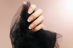 Close-up of a hand with neatly manicured nails holding a black mesh fabric.