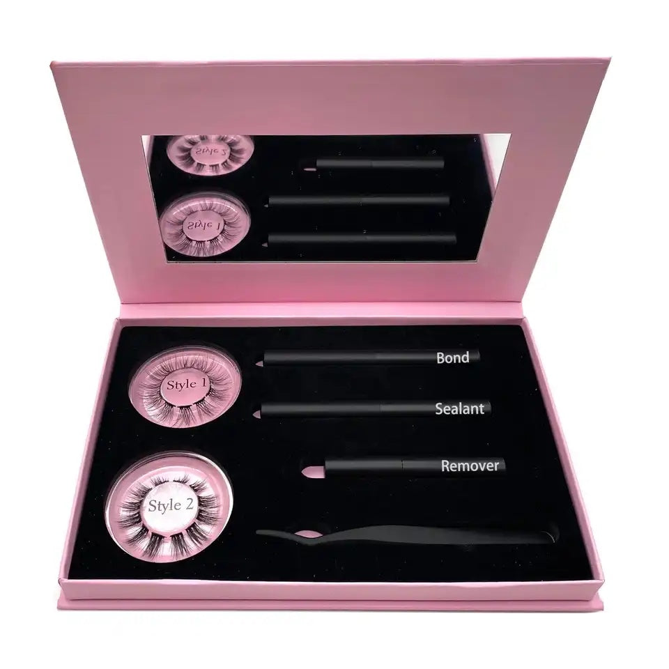 A magnetic lashes kit in a pink box, including a mirror, a container with false eyelashes, a tube of glue, and a brush.