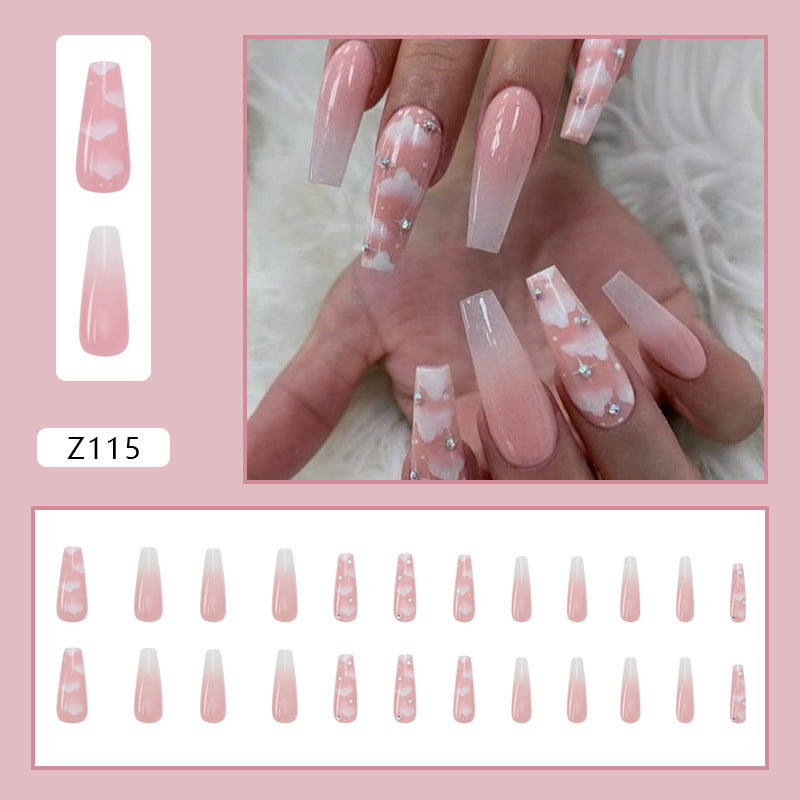 A set of false nails with a pink cloud design and rhinestone embellishments.