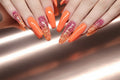 A set of press-on nails in various colors including pink, orange, yellow, blue, and purple, displayed on a furry surface.