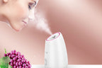 White humidifier with steam, grapes, and a woman's face on a pink background