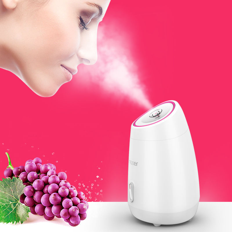 White humidifier with steam, grapes, and a woman's face on a pink background