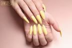 Yellow nail polish set on a hand with a plain background