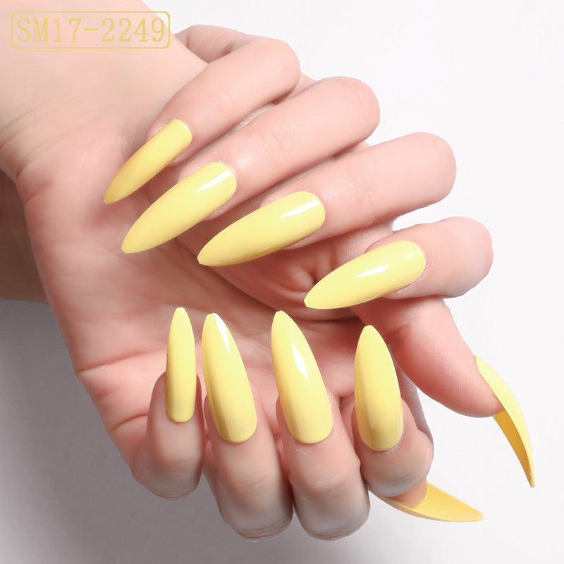 Yellow nail polish set on a hand with a plain background